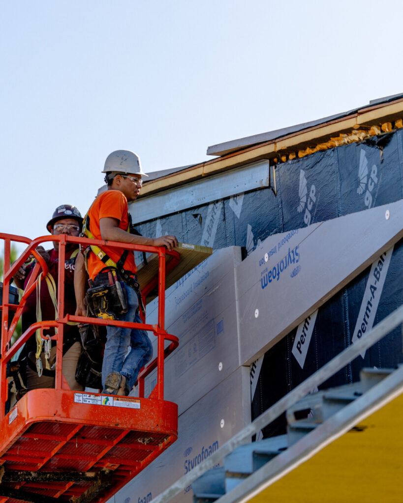 Contractors installing exterior wall insulation panels from a scissor lift.